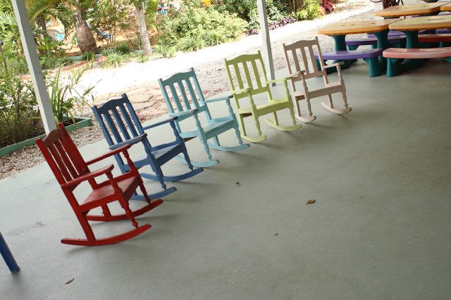 Colorful child-sized rocking chairs lined up on the outdoor patio