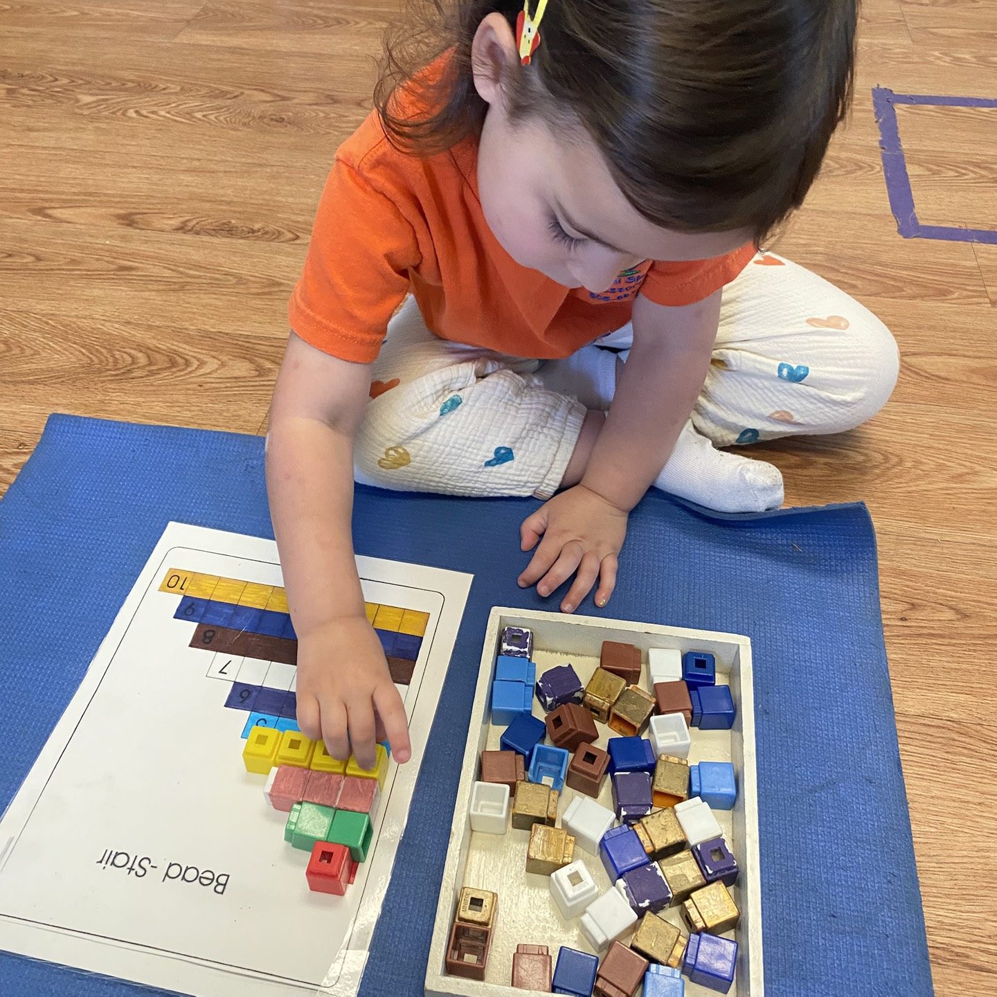 Boy stacking Montessori math cubes during a work period