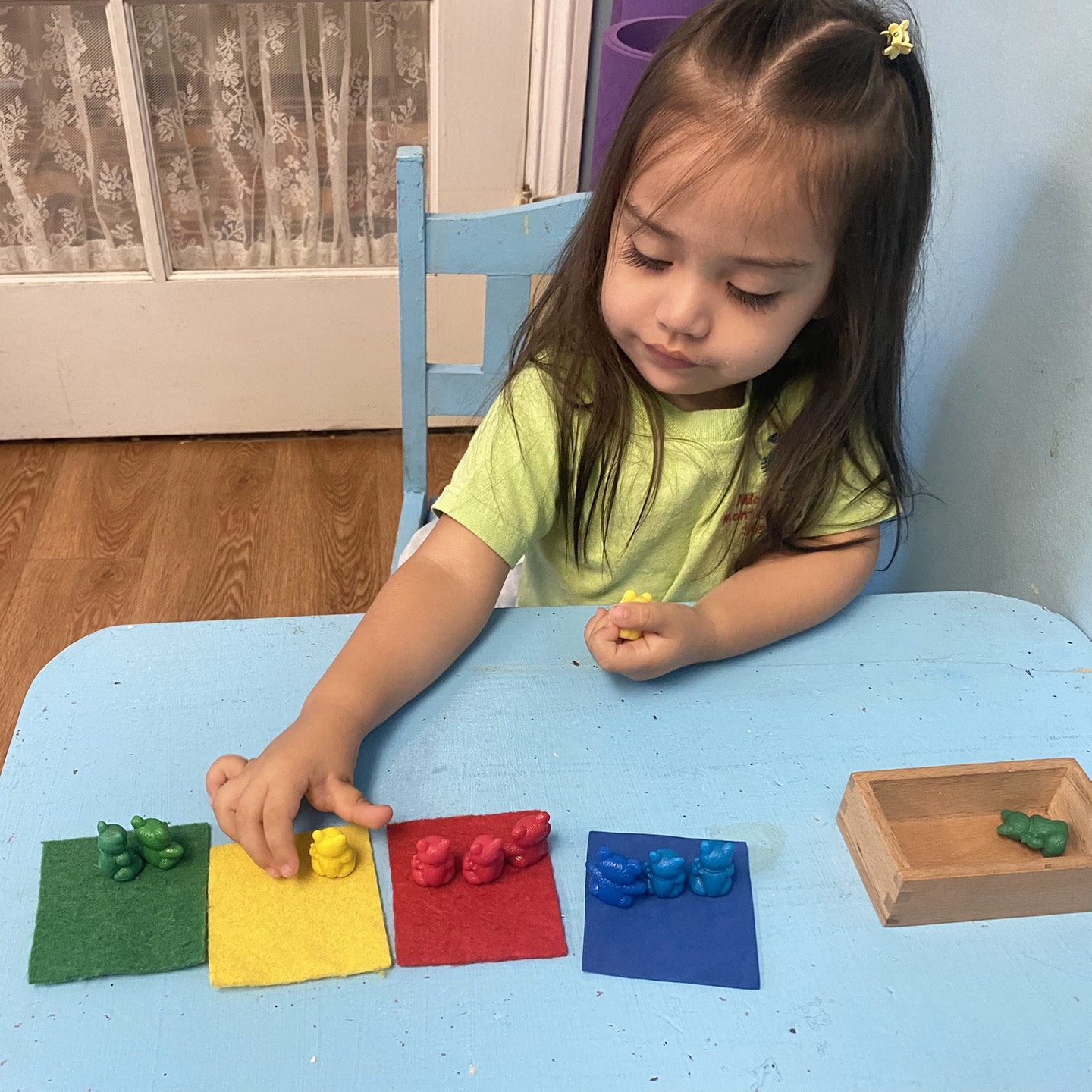 Preschool girl sorting objects by color at a low classroom table