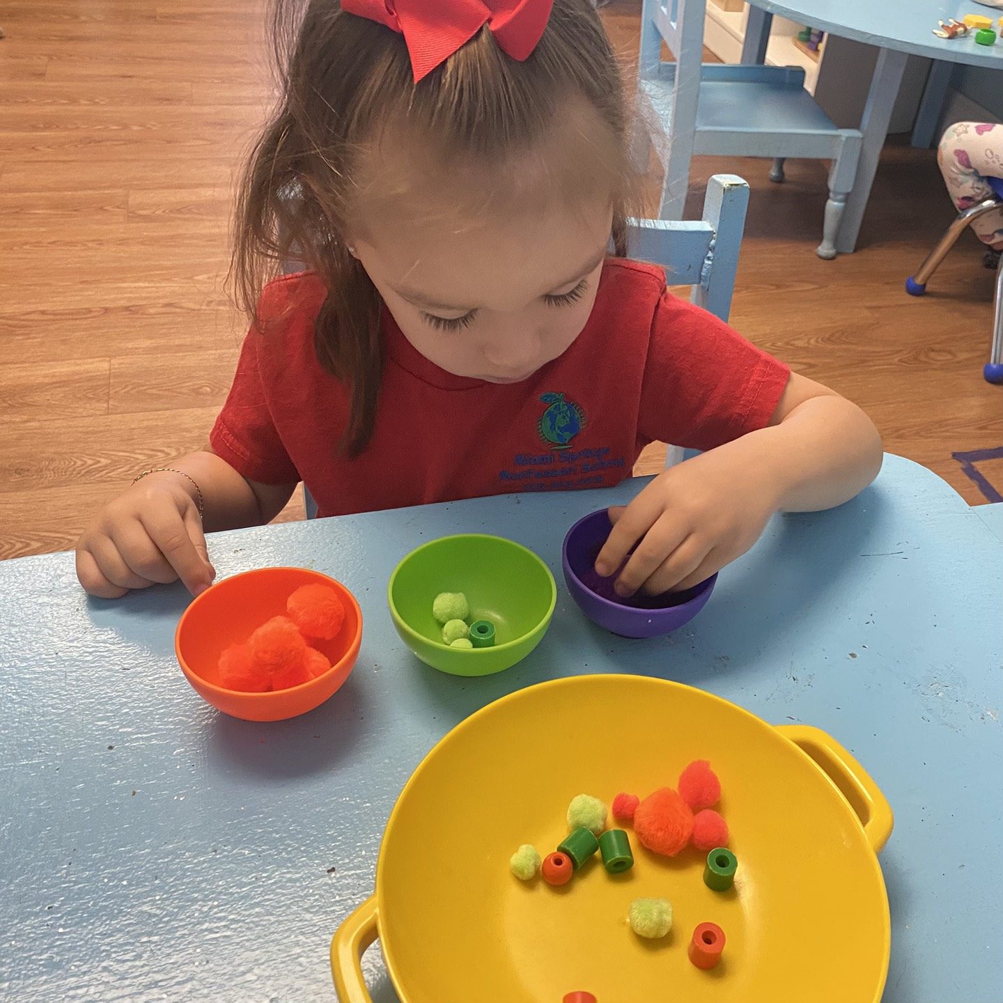 Girl sorting and counting colorful beads into bowls