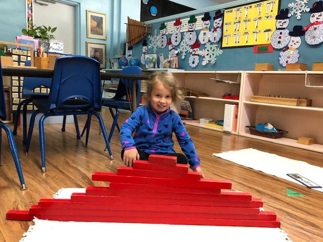 Girl concentrating on Montessori red rods work in the classroom