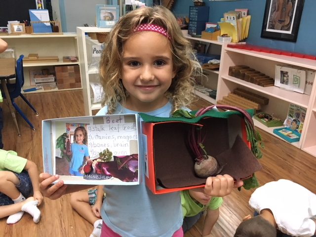 Girl proudly showing a book she is reading in the classroom